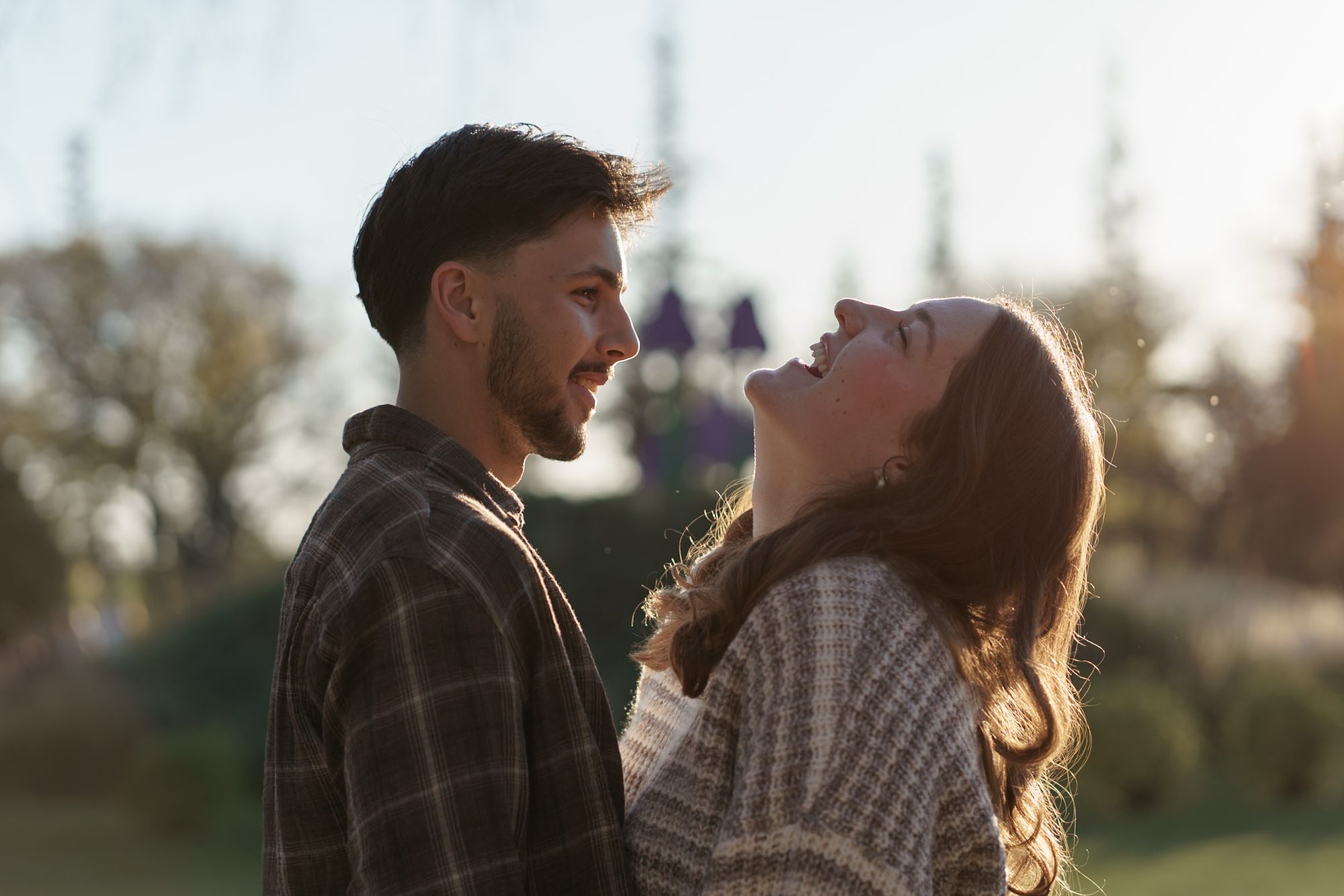 Couple laughing together in golden autumn light during a Winnipeg engagement session