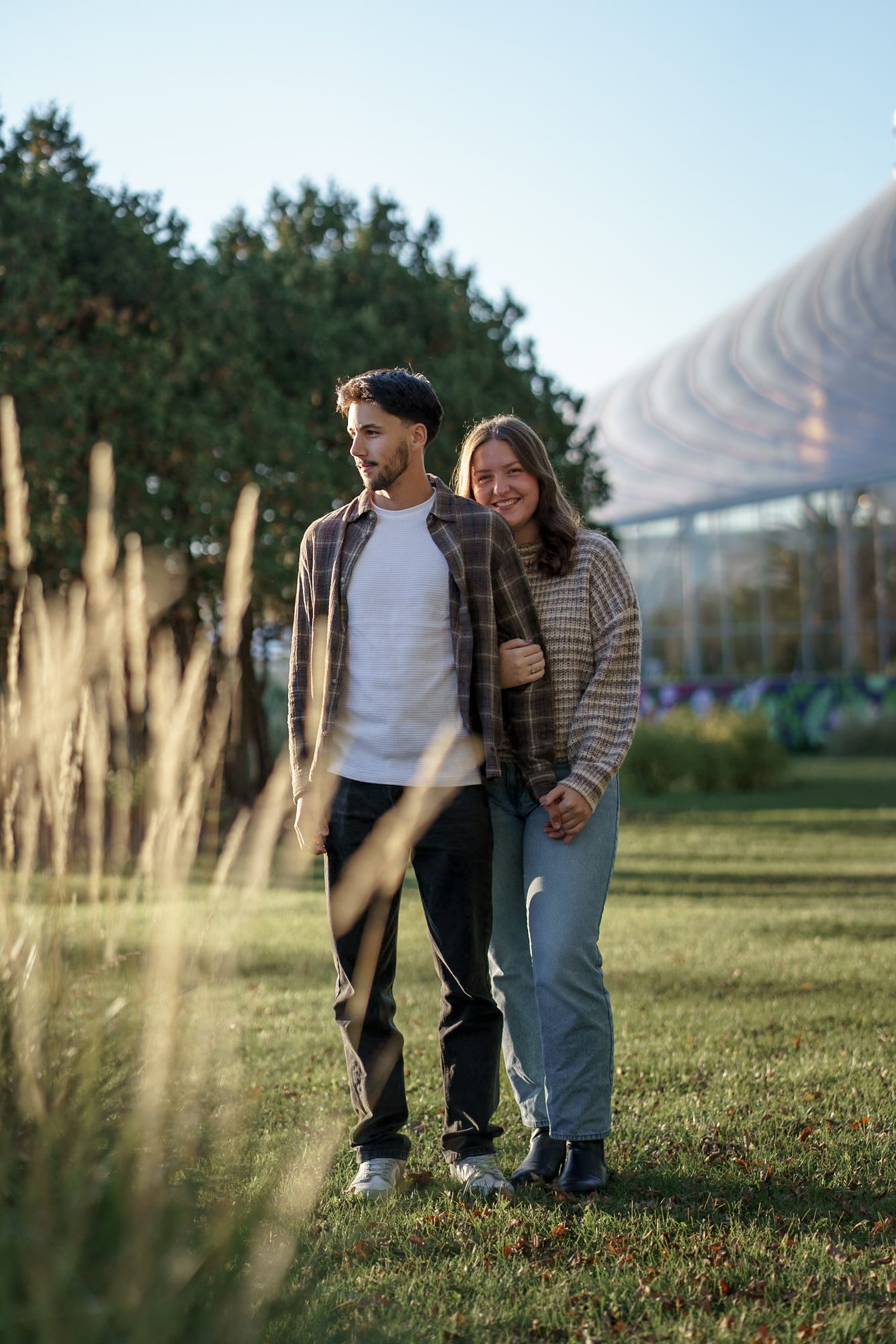 Couple walking through tall autumn grasses during a Winnipeg engagement session