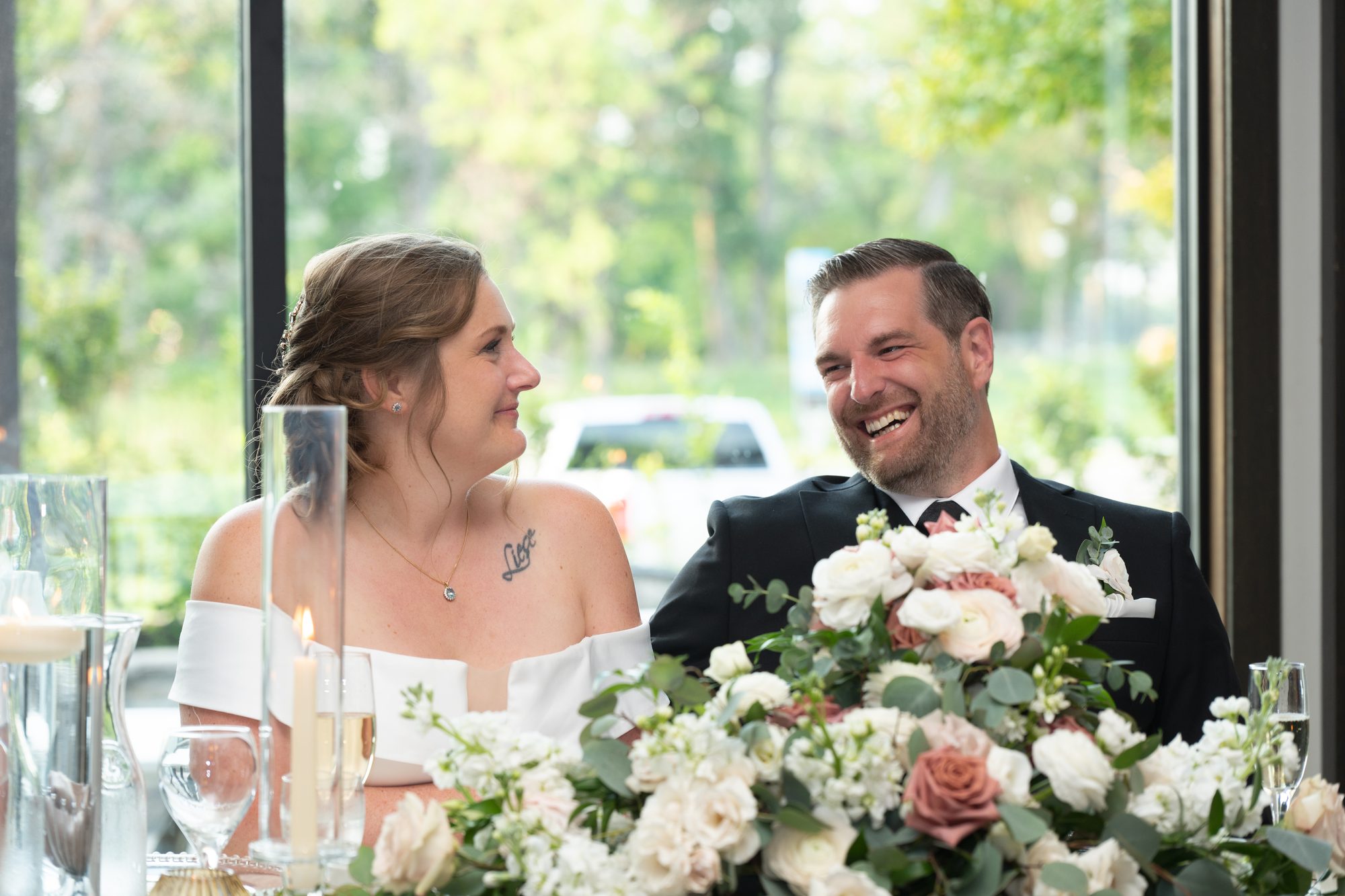 Bride and groom laughing together during speeches at Breezy Bend Country Club, Winnipeg
