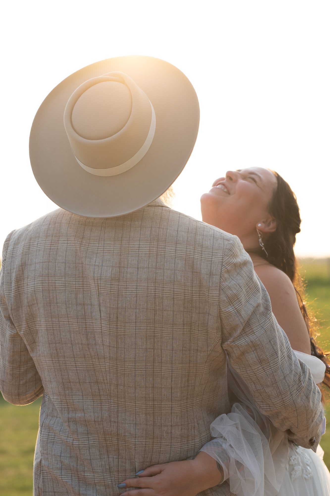 Bride laughing in her groom's arms at golden hour at an outdoor Manitoba wedding