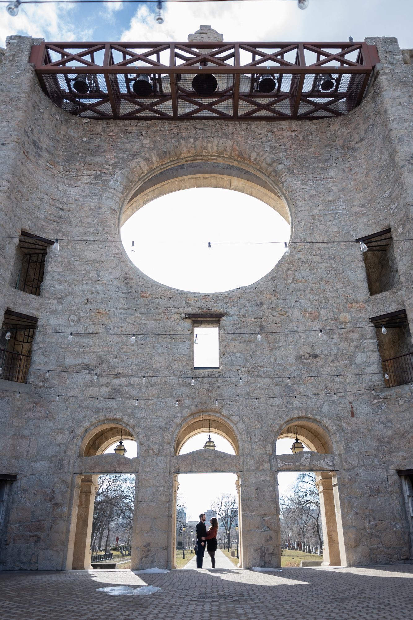 Inside the St. Boniface Cathedral ruins, looking up at the rose window opening and stone arches with a couple framed in the far archway