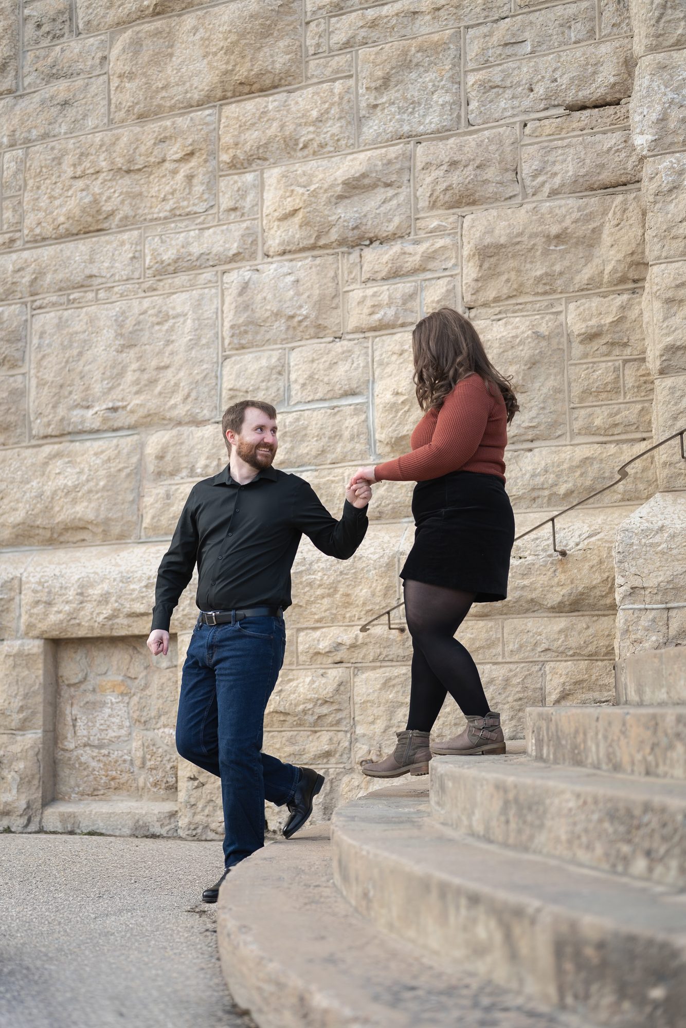 Couple walking up the stone side stairs at the St. Boniface Cathedral ruins during an engagement session