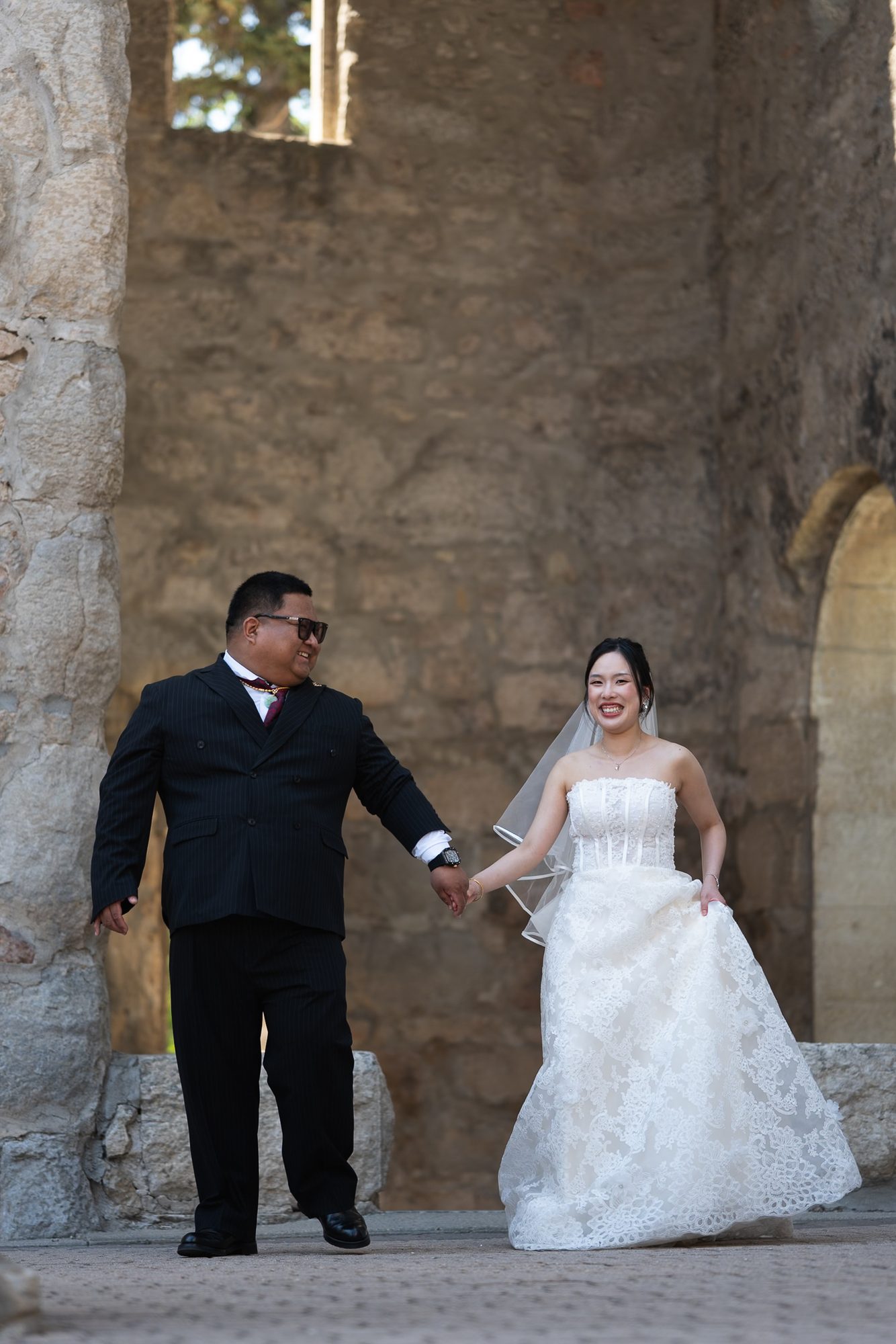 Bride and groom framed between stone columns inside the St. Boniface Cathedral ruins